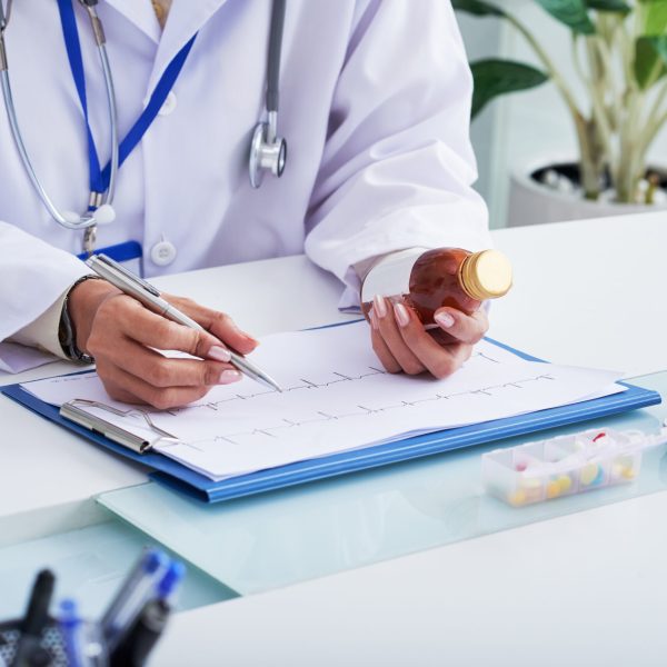 Close-up image of doctor prescribing medicine after checking cardiogram